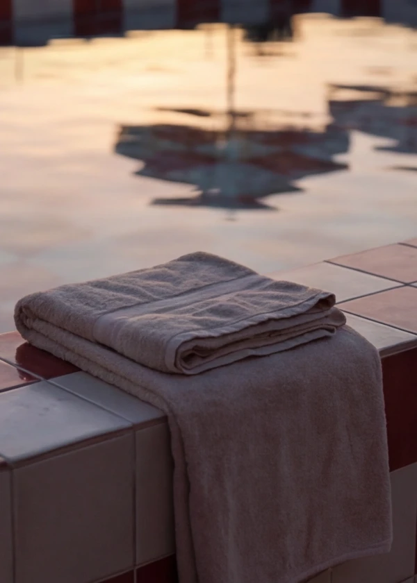 Toalla doblada sobre el borde de una piscina al atardecer.