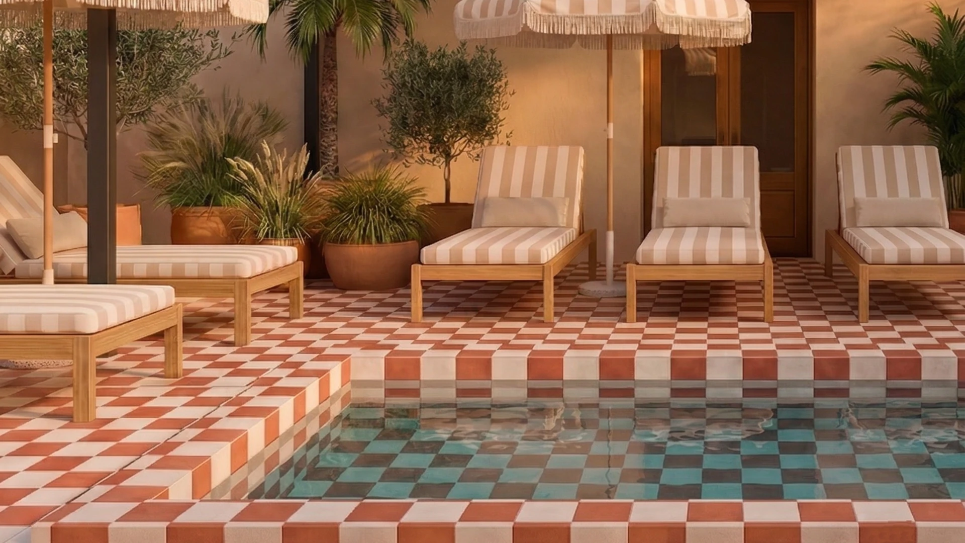 Terraza con piscina y tumbonas sobre suelo de cuadros, rodeada de plantas y sombrillas.