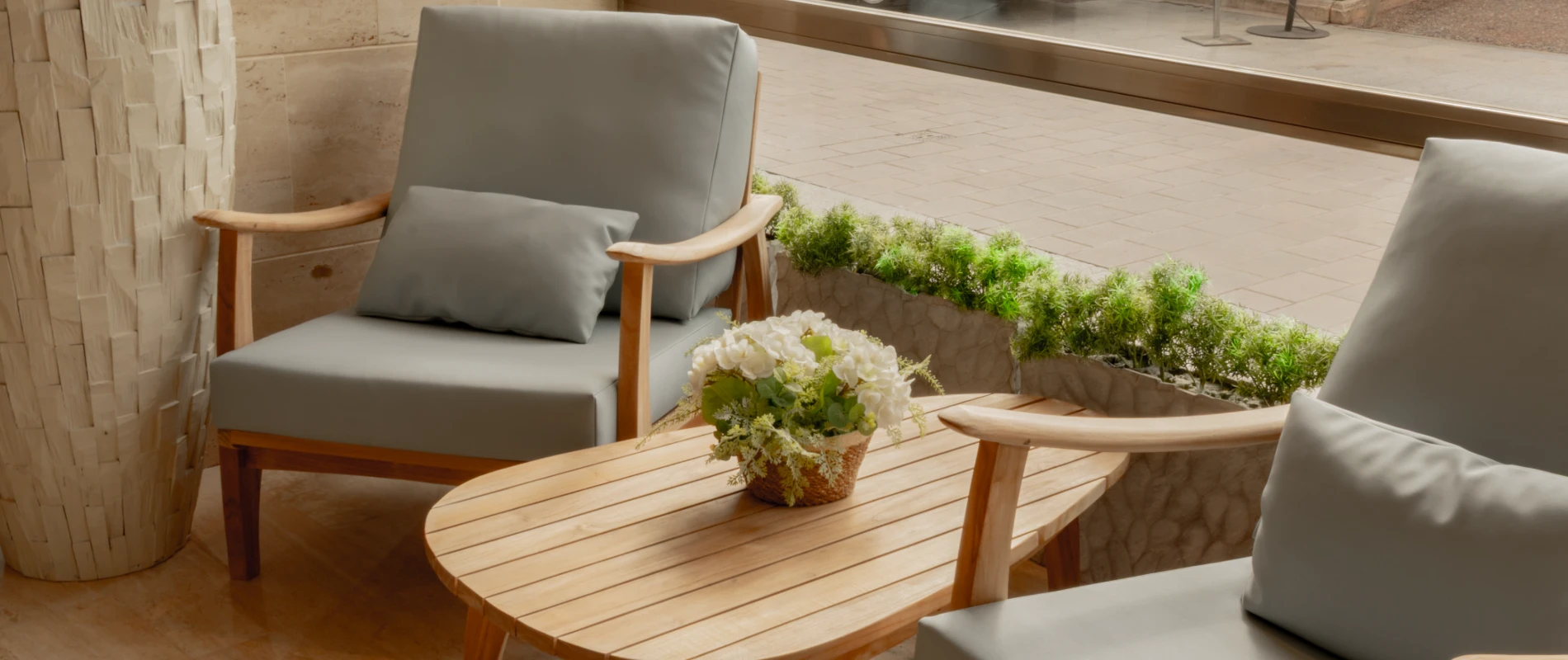 Sala con sillones grises, mesa de centro y planta decorativa frente a una ventana.
