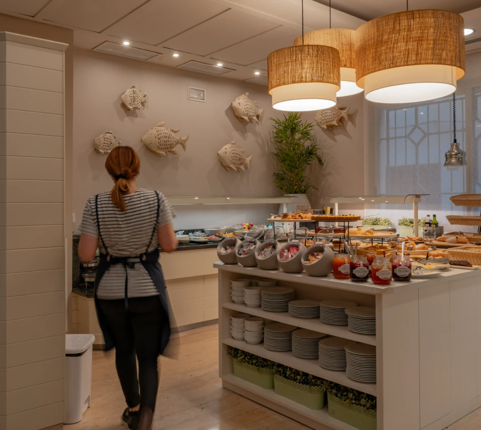 Una persona en una cocina moderna con decoraci&oacute;n de peces y buffet de desayuno.