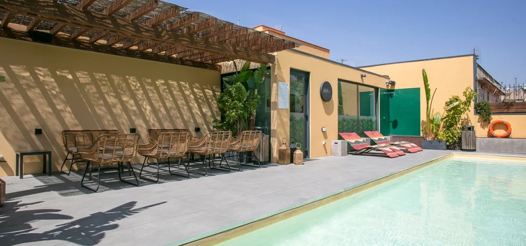 Patio con piscina y tumbonas, p&eacute;rgola y sillas junto a paredes de colores