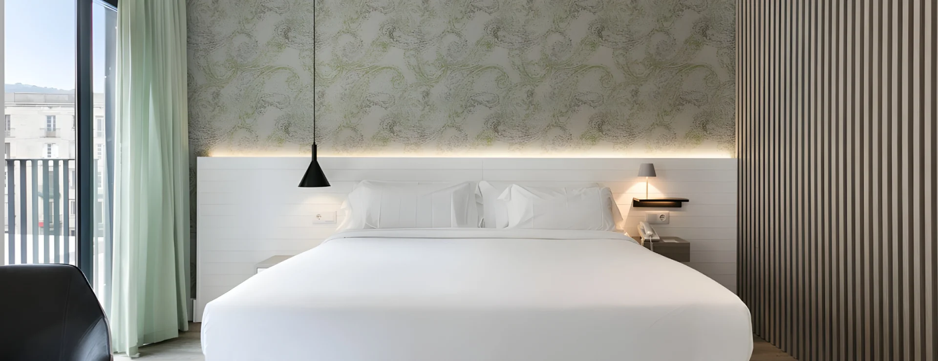 Habitaci&oacute;n de hotel moderna con cama blanca y cortinas verdes.