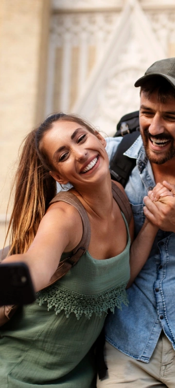Pareja sonriente con mochila, selfie en la calle.