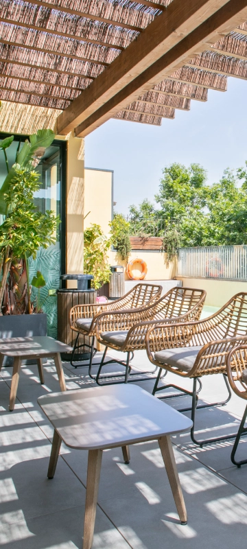 Terraza con mesa y sillas, sombrilla de madera y plantas junto a piscina
