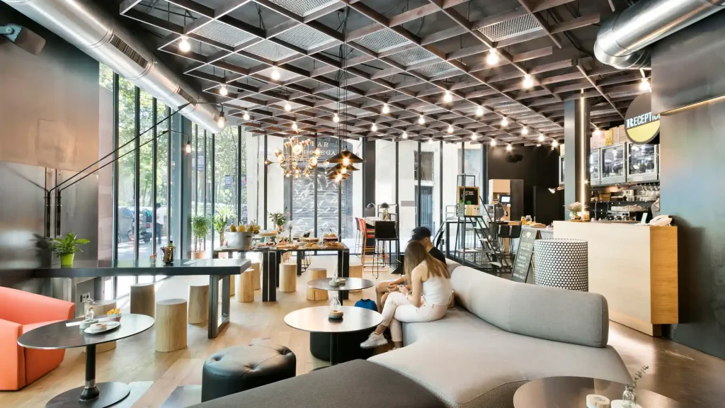 Sal&oacute;n moderno con iluminaci&oacute;n colgante, barra y recepci&oacute;n con mujer sentada