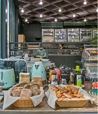 Vitrina de pan y bollería en cafetería, con mesas y luces interiores