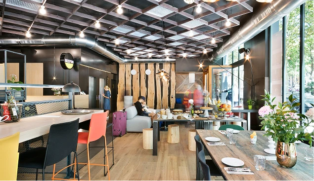 Sala creativa con mesas, sillas y lámparas bajo techo de metal.