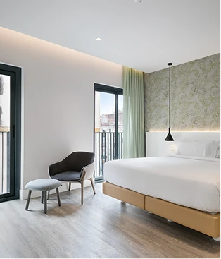 Dormitorio moderno con cama blanca, silla y ventana, luz cálida y verde.
