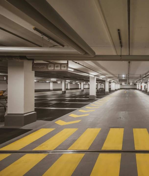 Estacionamiento subterr&aacute;neo con l&iacute;neas amarillas de se&ntilde;alizaci&oacute;n y columnas.