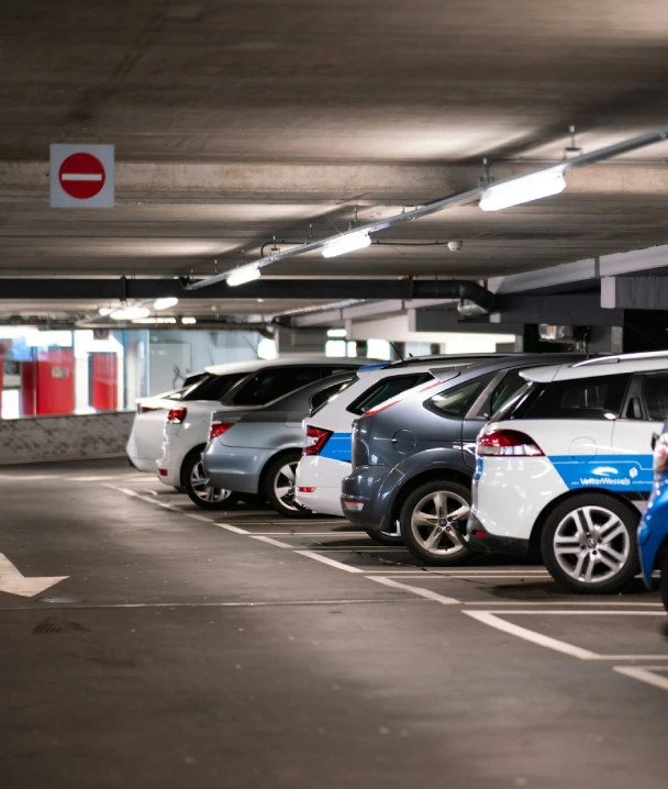 Fila de coches en un aparcamiento subterr&aacute;neo, con luces y se&ntilde;al de salida