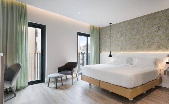 Dormitorio moderno con cama doble, sillones y puertas al balc&oacute;n.