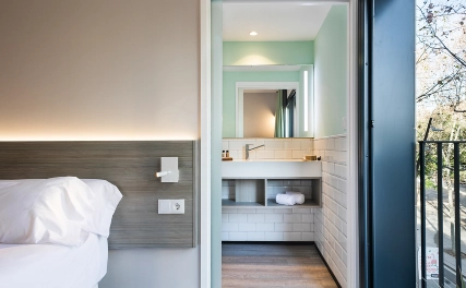 Dormitorio con cama y ba&ntilde;o al fondo, en suite moderna.