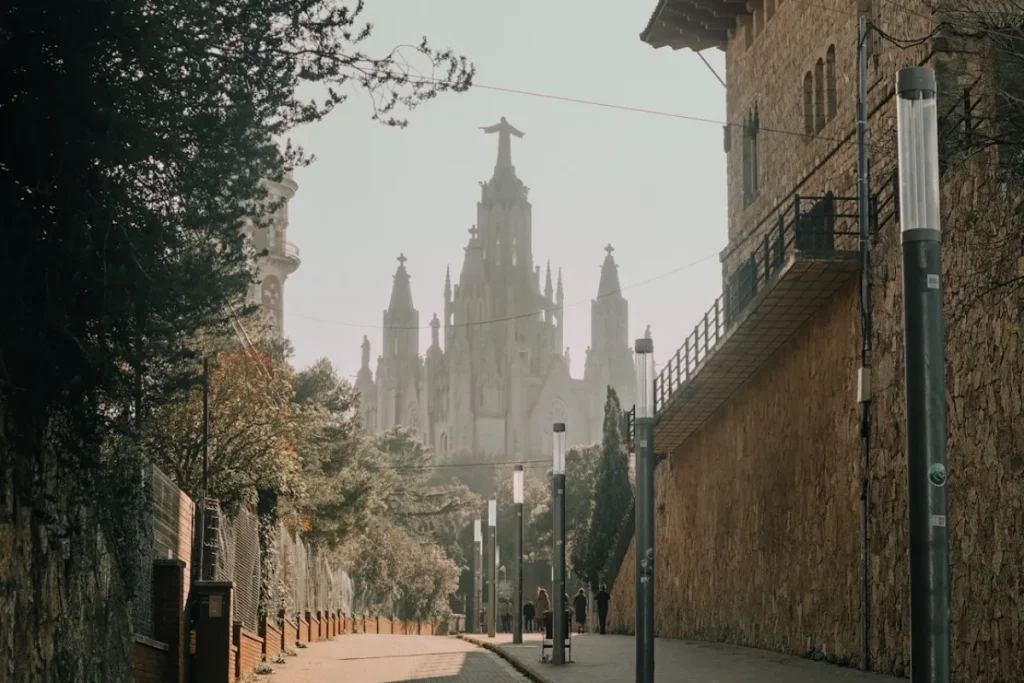 Calle con torre g&oacute;tica al fondo y edificios de piedra, con niebla.