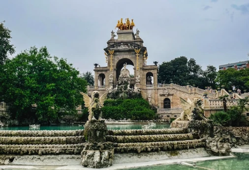 Fuente y monumento con estatuas en un jard&iacute;n, bajo cielo despejado