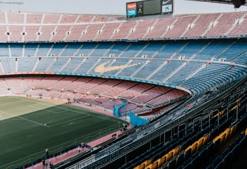 Estadio vac&iacute;o con grada escalonada y campo verde de f&uacute;tbol al fondo