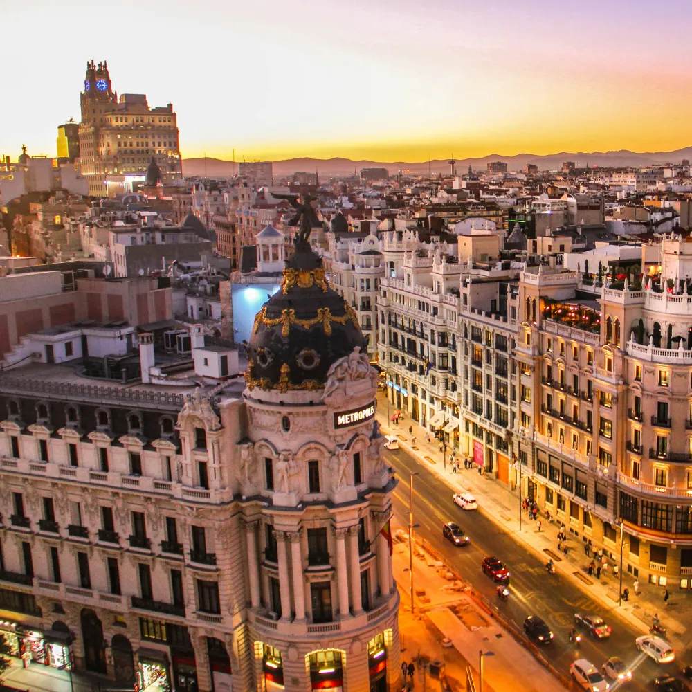 Vista a&eacute;rea de Madrid al atardecer, con el edificio Metr&oacute;polis iluminado.