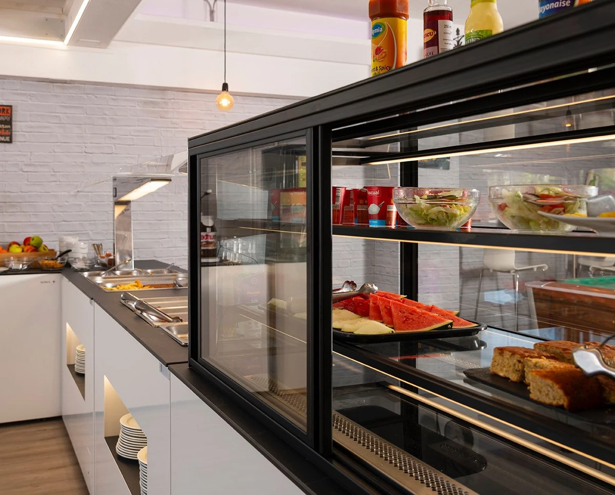 Vitrina de buffet con panes y ensaladas, en cocina de restaurante