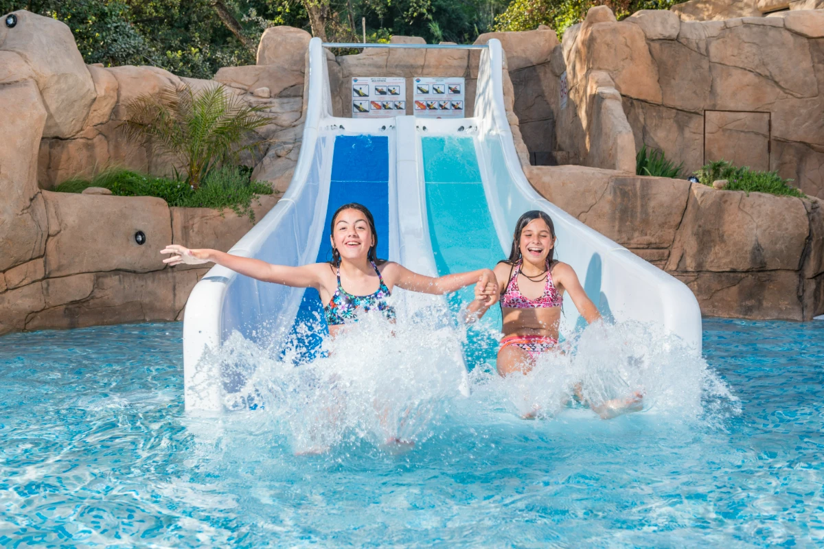 Dos niñas se divierten en una piscina con tobogán de agua.
