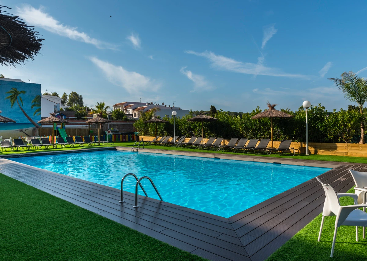 Piscina azul con tumbonas, césped y cielo despejado en un hotel.