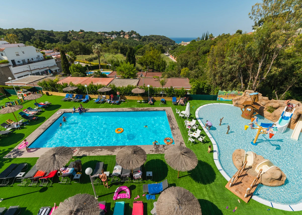 Vista aérea de una piscina familiar con parque infantil y jardín verde al aire libre