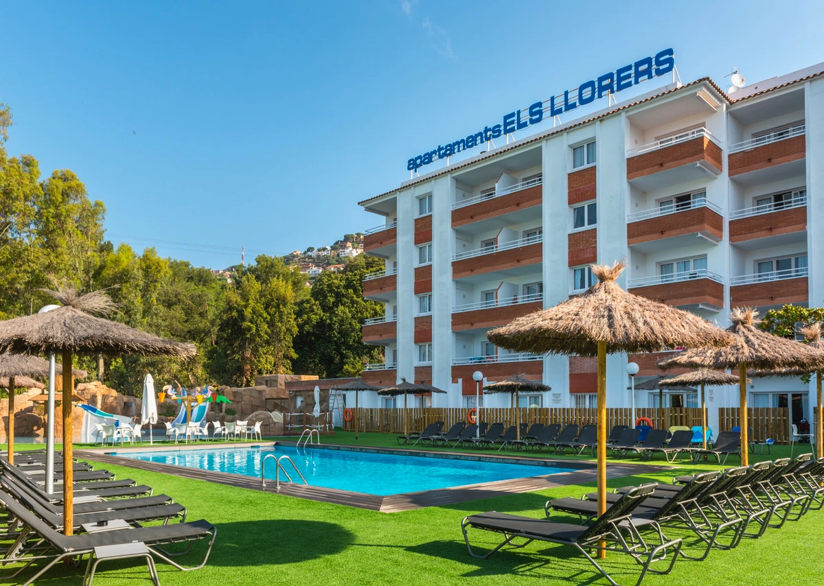 Piscina al aire libre con tumbonas y edificio de apartamentos junto al jardín