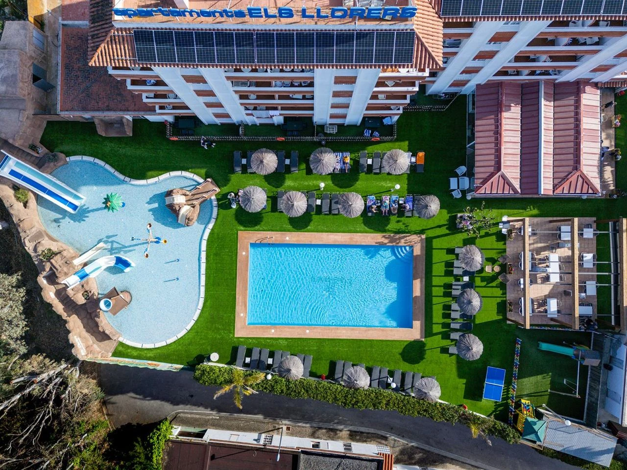 Vista aérea de una villa con piscina, jardines, tumbonas y zona de alberca.
