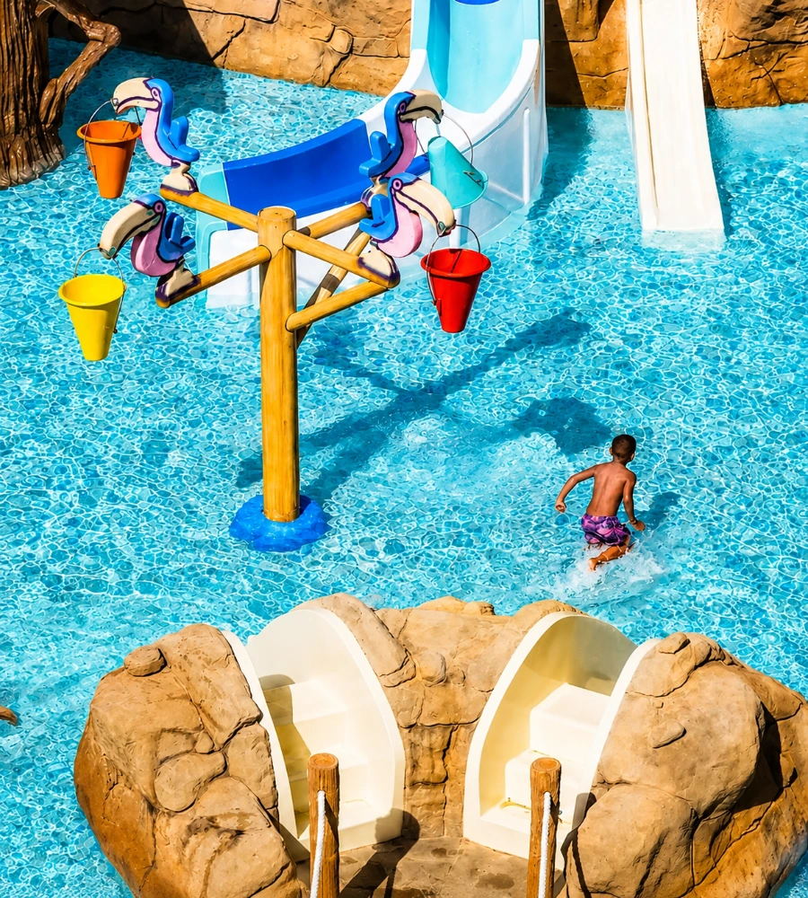 Piscina con fuentes y pececillos, ni&ntilde;o peque&ntilde;o nadando y cubos de colores