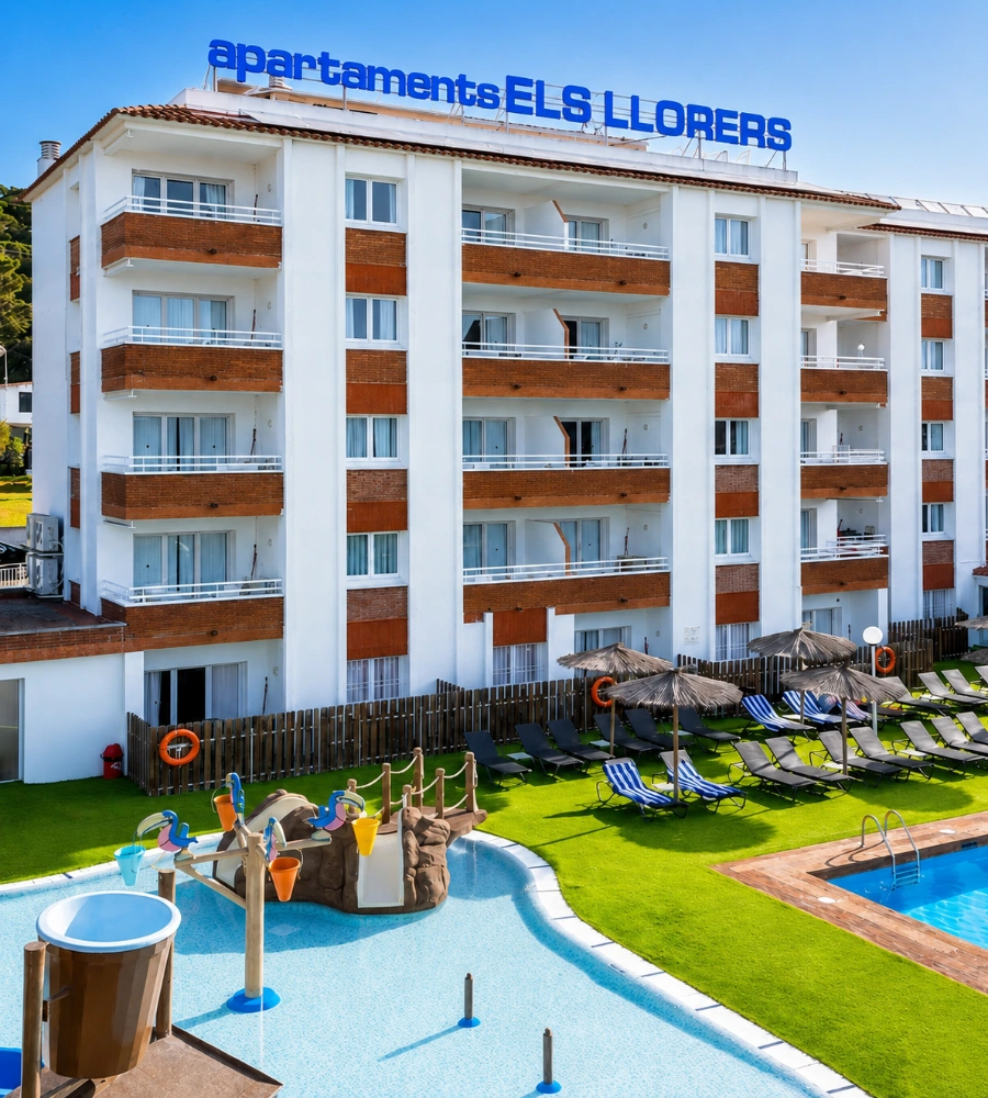 Piscina y jard&iacute;n con tumbonas frente a un edificio de apartamentos en Lloret de Mar