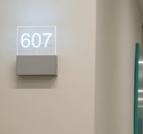 N&uacute;mero 607 en placa iluminada junto a la pared de un pasillo