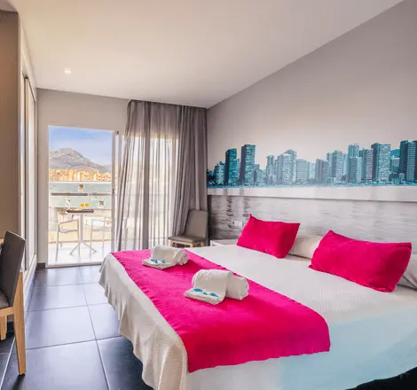 Dormitorio moderno con cama blanca y cojines fucsia, vista a la ciudad