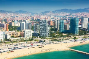 Vista aérea de una ciudad costera con playa, edificios y tráfico de autos.
