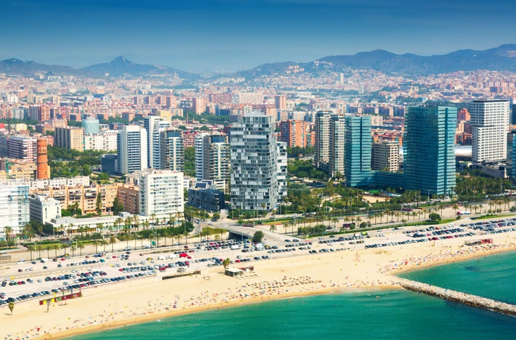 Vista a&eacute;rea de una ciudad costera con playa, edificios y tr&aacute;fico de autos.