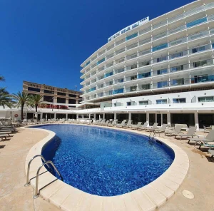 Piscina azul de hotel con tumbonas y edificio de varios pisos al cielo azul