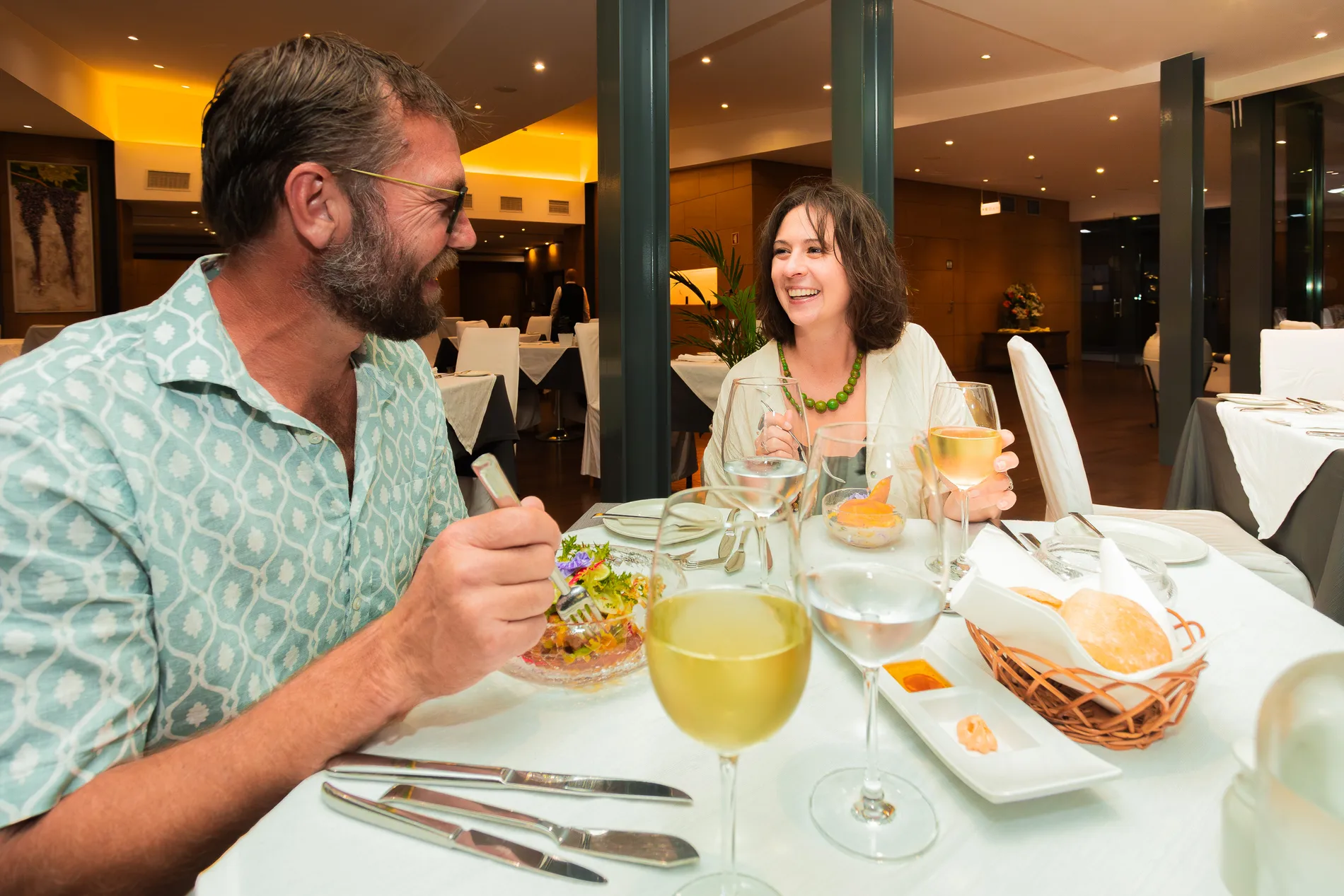 Casal sorridente janta em um restaurante elegante.