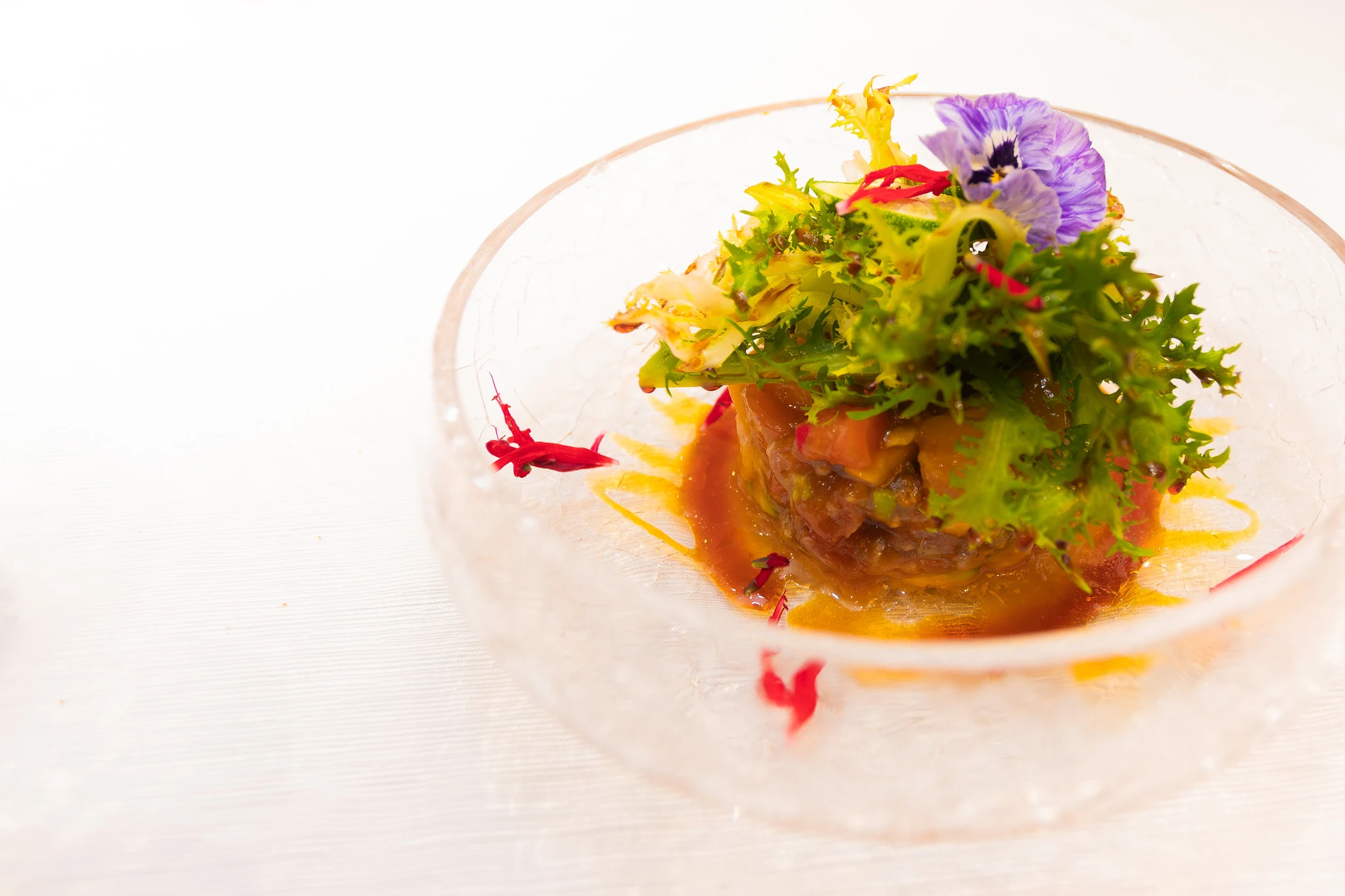 Prato gourmet com salada de folhas verdes e flor comest&iacute;vel roxa.