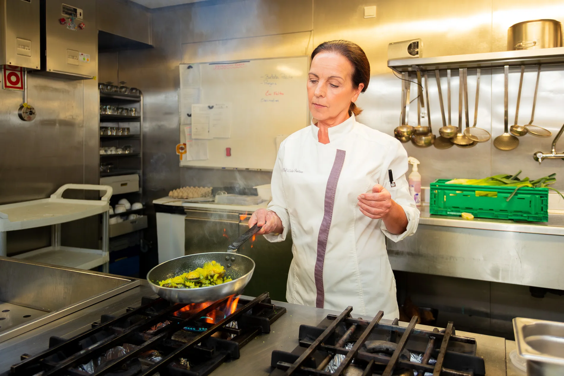 Chef cozinhando em cozinha comercial com panela no fog&atilde;o.