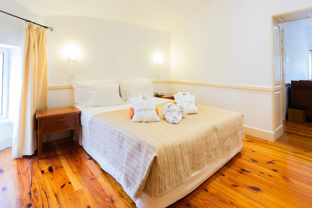 Quarto de hotel aconchegante, cama de casal e toalhas decorativas.