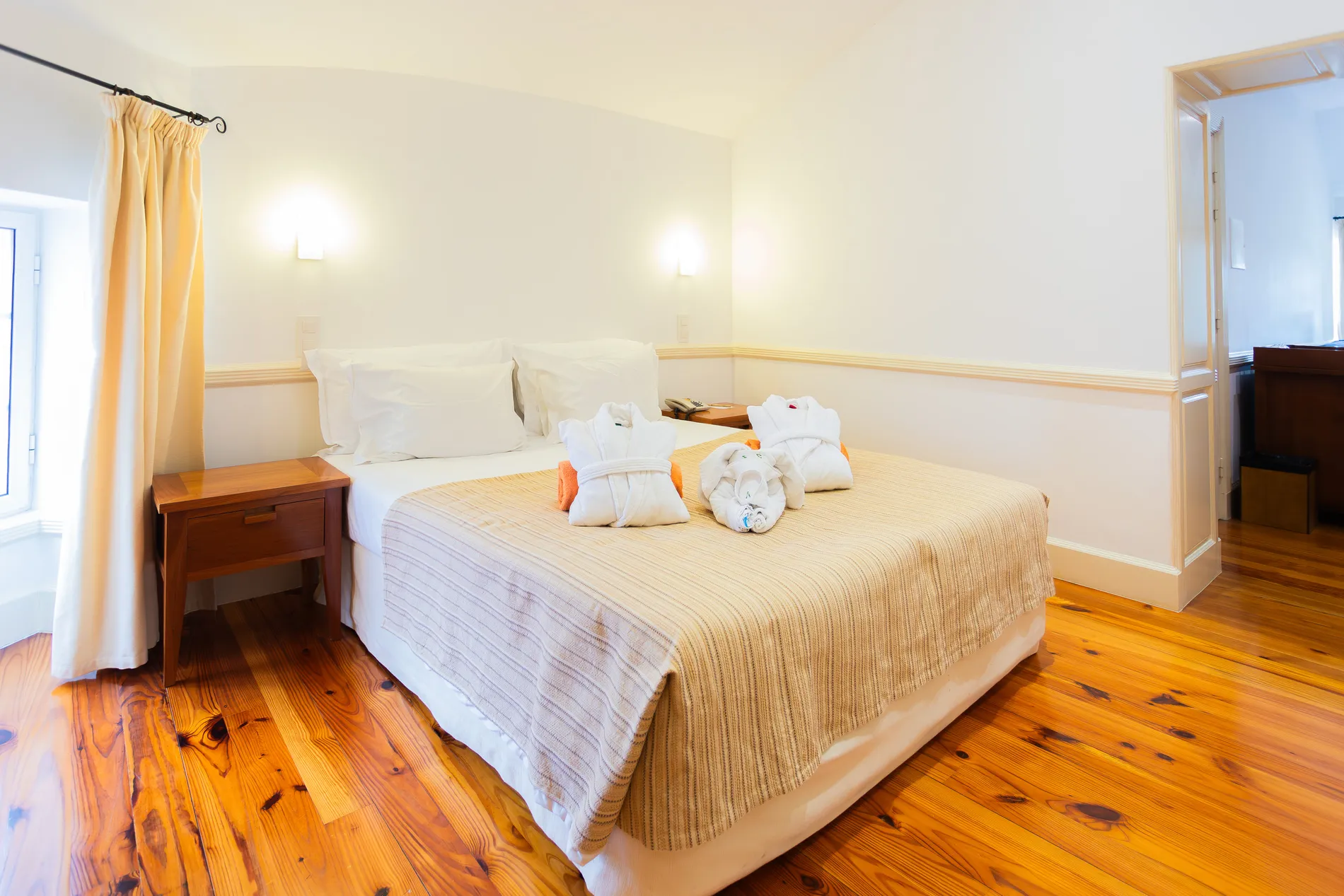 Quarto aconchegante com cama arrumada e luz suave ao fundo.