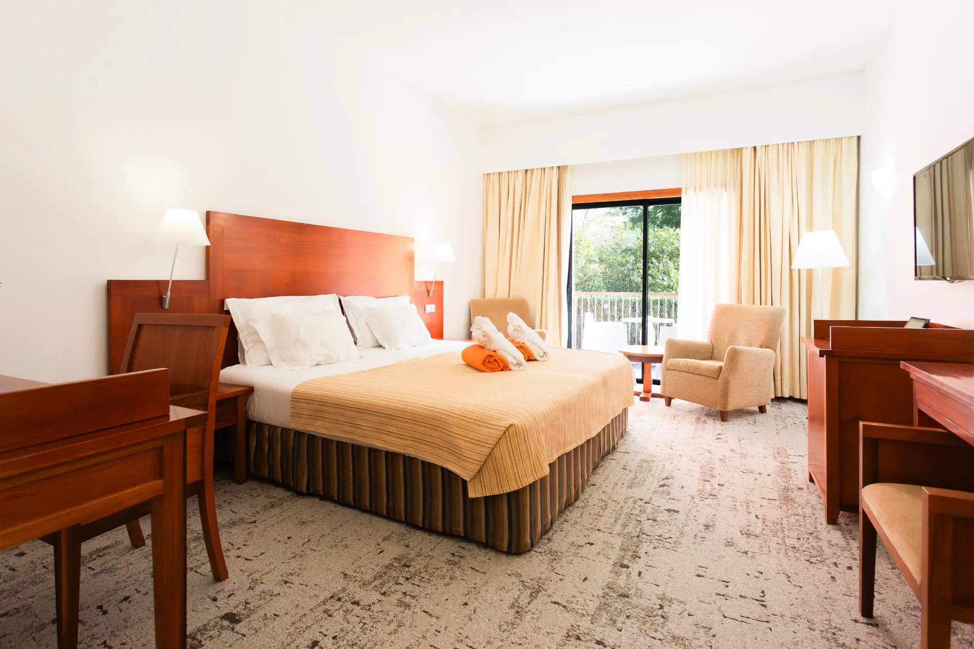 Quarto de hotel elegante com cama, poltrona e janela de vidro.