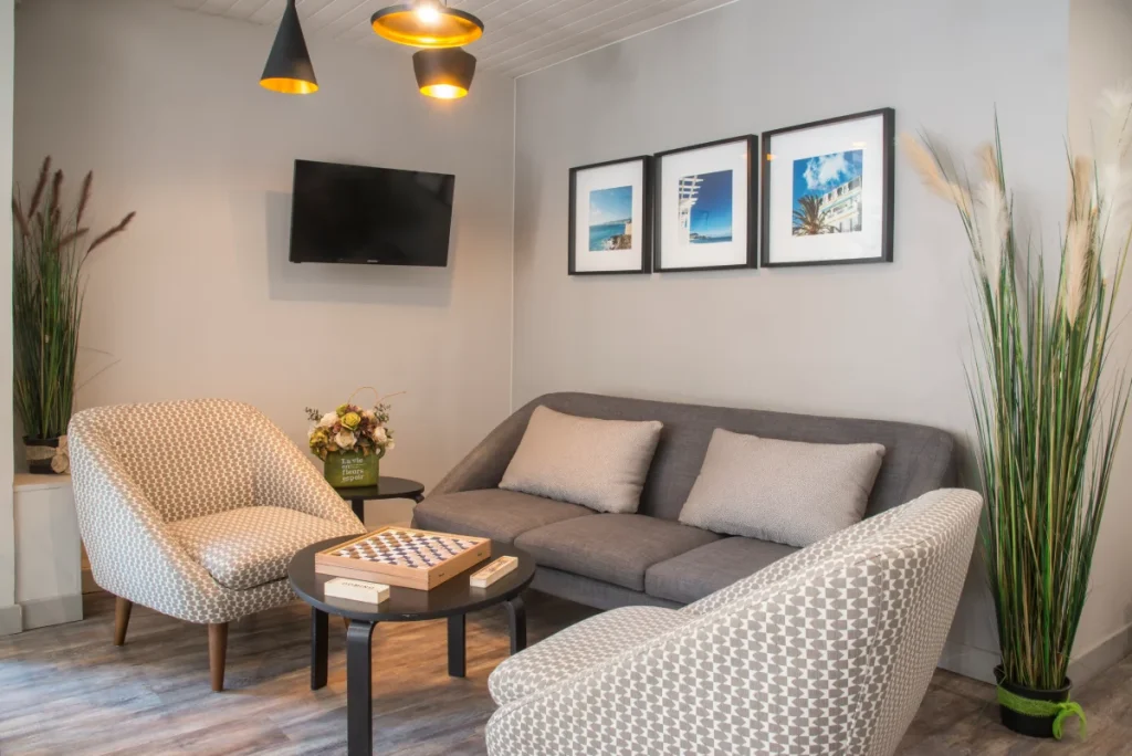 Sala moderna con sillones, sof&aacute; gris, mesa de centro y cuadros decorativos.