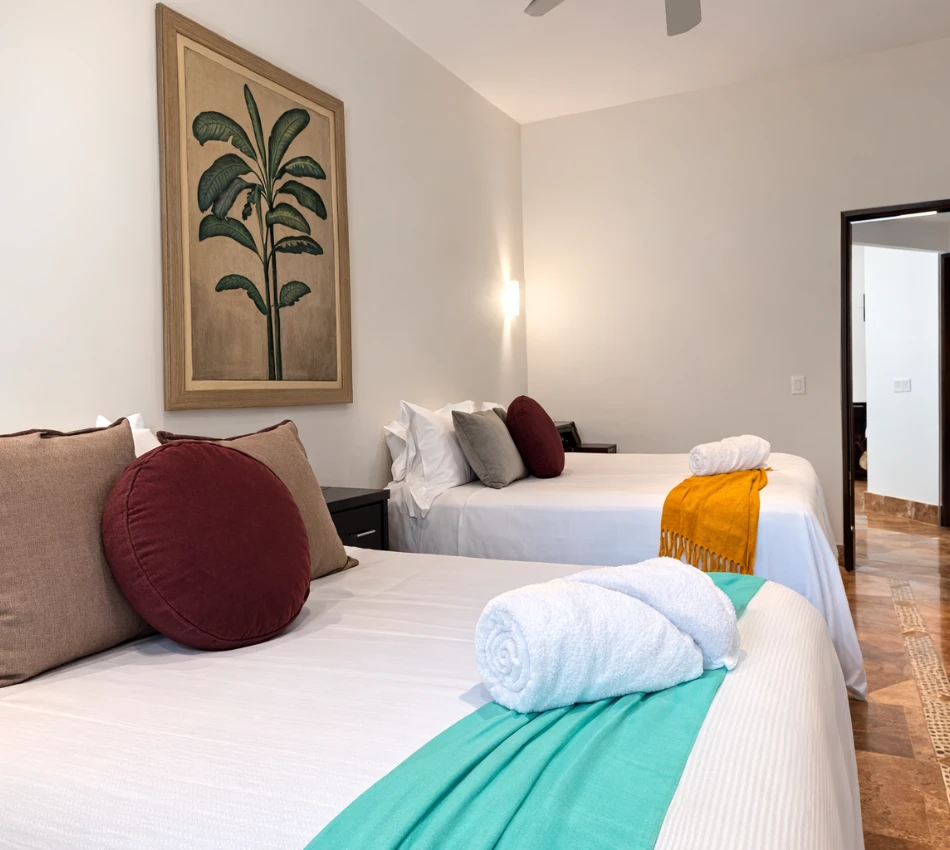 Dos camas con decoraci&oacute;n minimalista en habitaci&oacute;n de hotel.