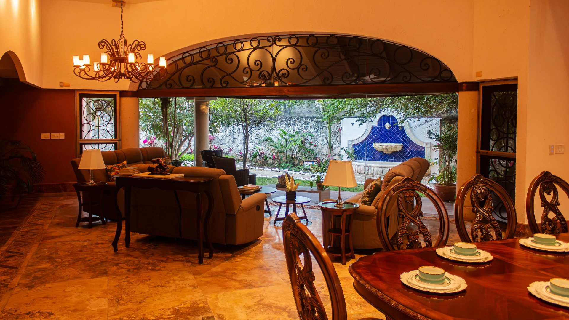 Sala acogedora con candelabro, vista al jard&iacute;n y decoraci&oacute;n cl&aacute;sica.