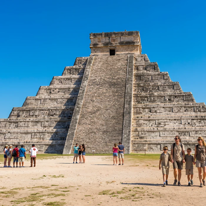 Personas frente a la pir&aacute;mide de Chich&eacute;n Itz&aacute; bajo un cielo despejado.