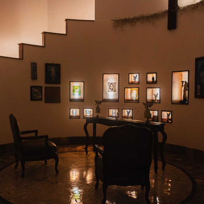 Sala con cuadros iluminados y muebles antiguos en ambiente acogedor.