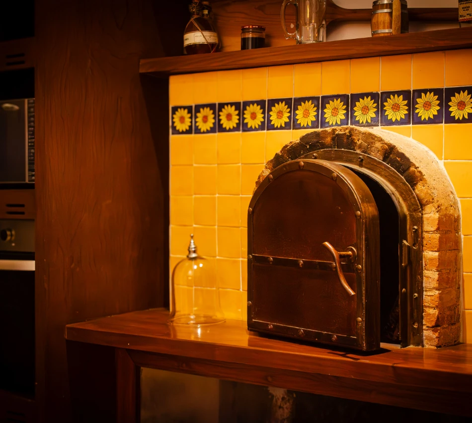 Horno de ladrillo con puerta de metal en cocina con mosaicos amarillos.