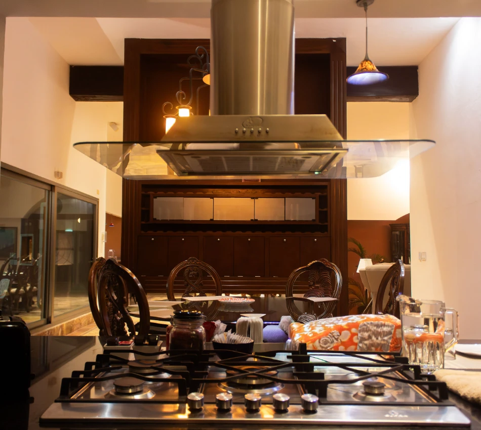 Cocina moderna con extractor y mesa decorada al fondo.