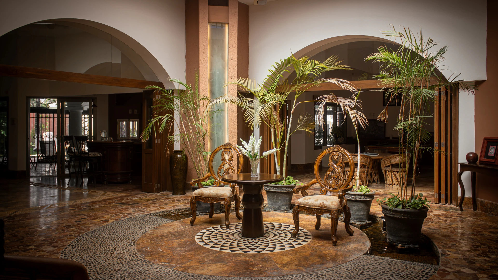Sala elegante con plantas, mesa y sillas cl&aacute;sicas en un entorno hogare&ntilde;o.
