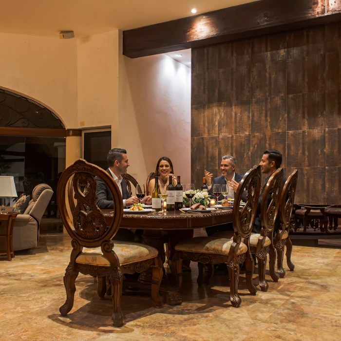 Grupo de personas cenando y conversando en un comedor elegante.