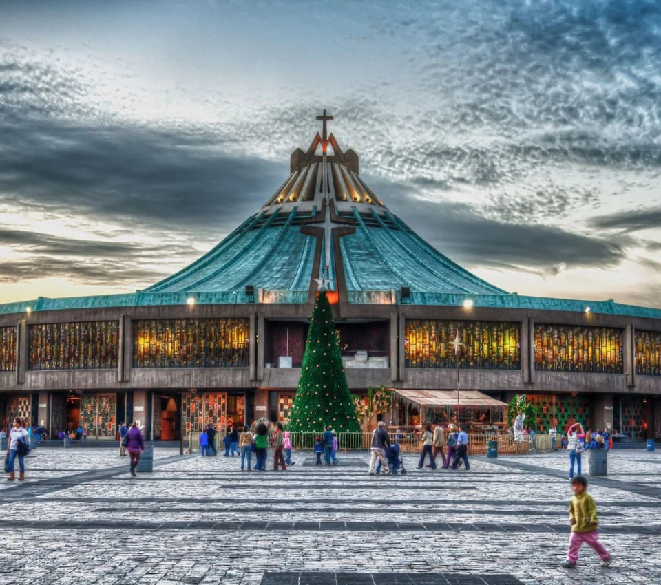 Bas&iacute;lica moderna con &aacute;rbol de Navidad y gente caminando en la explanada.
