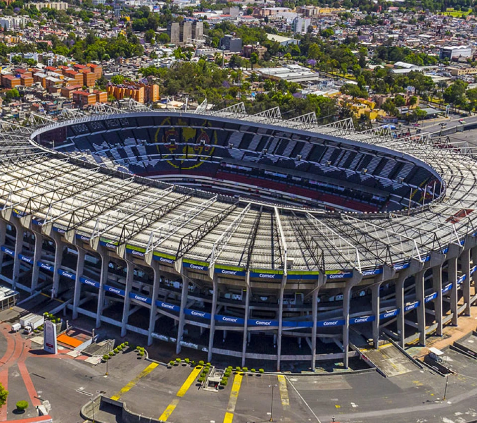 Estadio grande con techo de metal y ciudad al fondo.